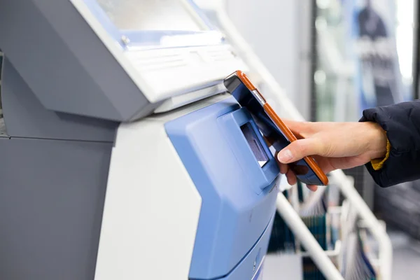 Woman paying on ticketing machine by NFC