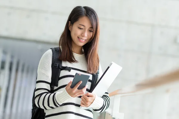 Female student with laptop using mobile phone