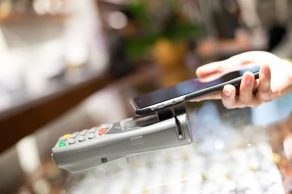 Woman using cellphone for paying the bill