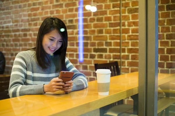 Woman using mobile phone at coffee shop