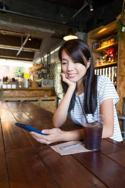 Woman enjoying coffee and using mobile phone