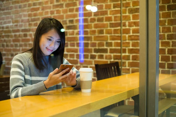 Woman using mobile phone in coffee shop