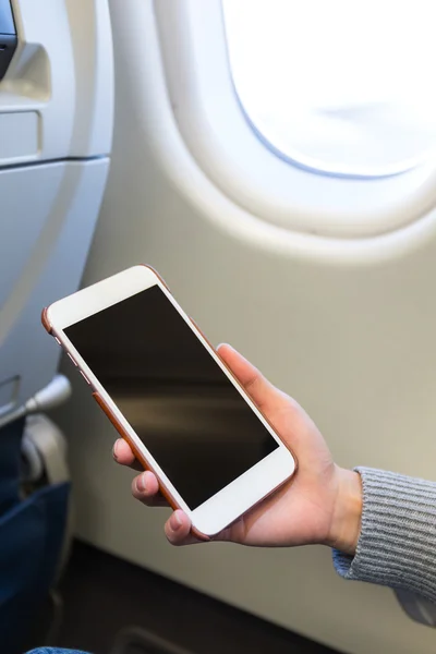 Woman using smartphone inside airplane