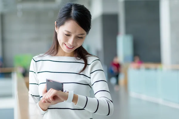 Woman connecting cellphone with smart watch