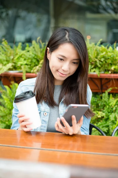 Woman looking at cellphone at outdoor coffee shop