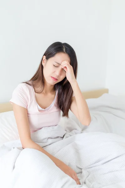 Woman feeling dizzy and sitting on bed