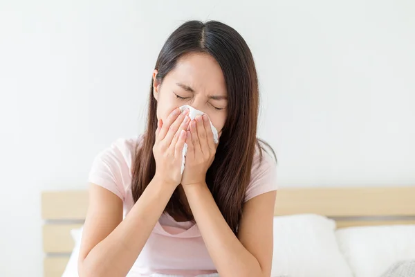 Sick woman sneezing into tissue