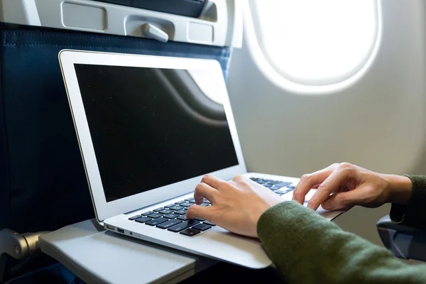 Woman using laptop in airplane