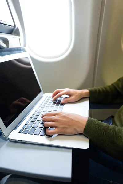 Woman working on laptop in  airplane