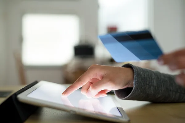 Woman using credit card to pay on tablet