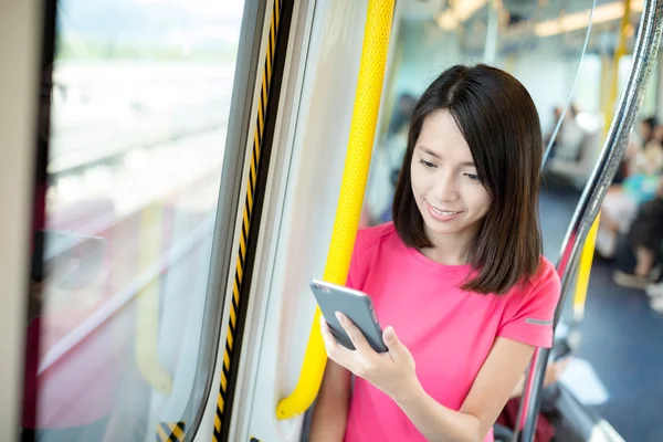 Woman using cellphone inside train compartment