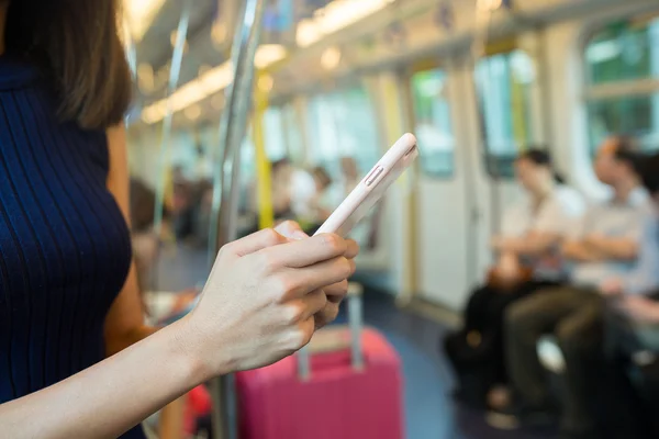Woman using mobile phone inside train compartment