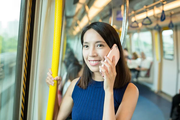 Woman talking on mobile phone inside train