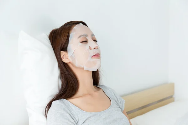 Asian woman on bed using mask