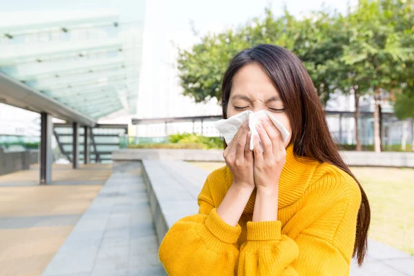 Sick woman with a cold blowing into tissue