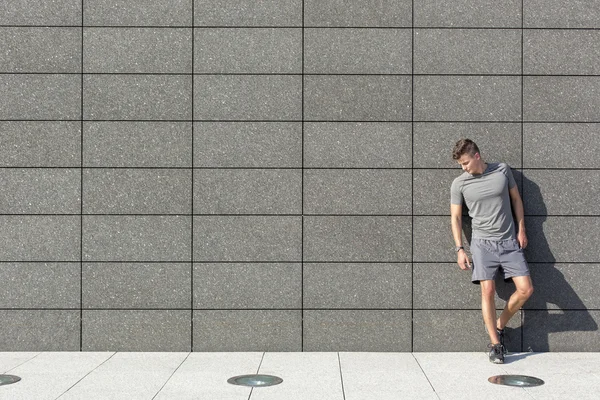 Sporty man leaning on wall