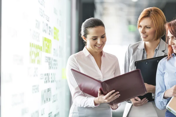 Businesswomen with file folders discussing