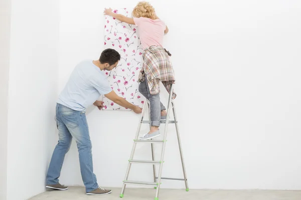 Couple applying wallpaper