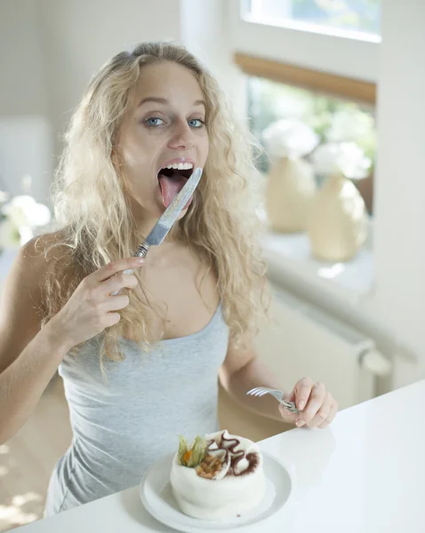 Woman with cake licking table knife