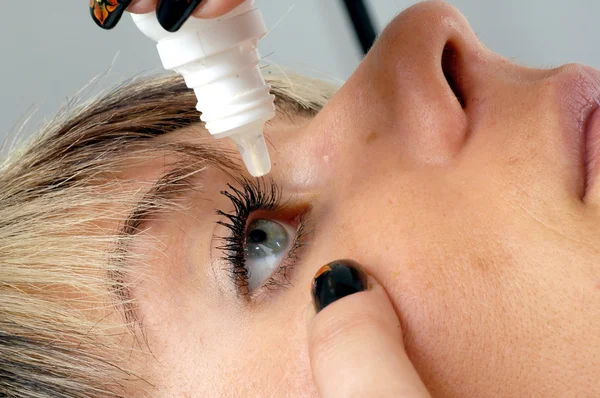 Woman applying eye drop