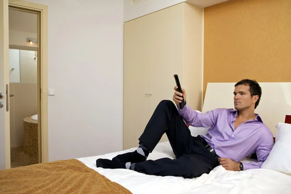 Man on bed holding remote control