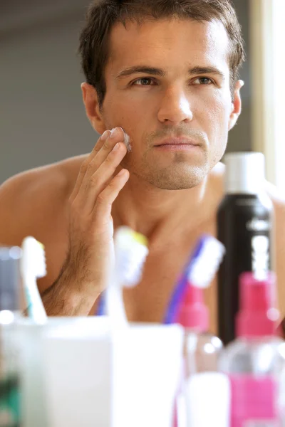 Man in mirror applying cream