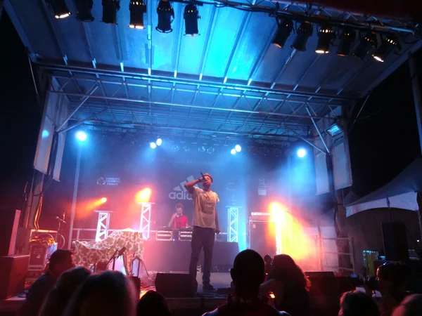 MC Yogi sings into mic as he preforms on stage with DJ Drez