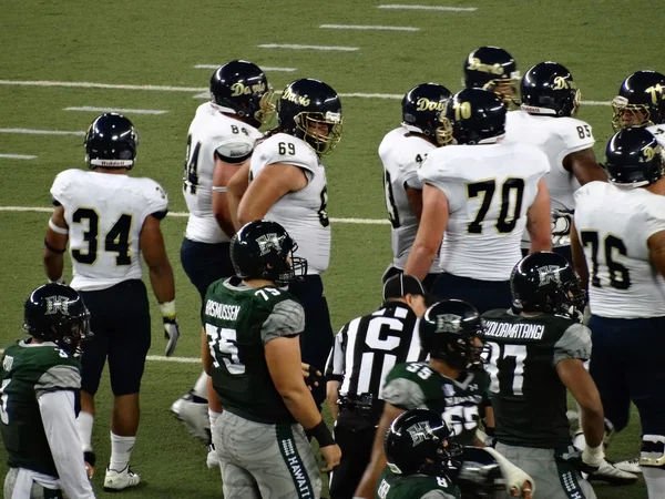 UH Football and UC Davis players standing after play during coll