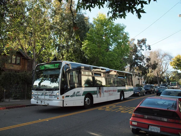 AC Transit bus with ads displayed on side driving down the stree