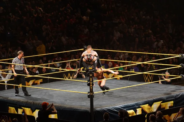 NXT male wrestler Finn Balor squats on top of ring ropes as Adri