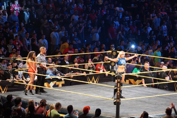 NXT Female wrestlers Charlotte Flair stands in ring with arms ex