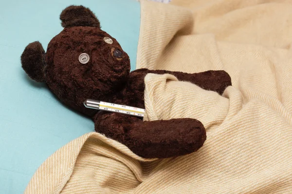 Big bear toy is sick with influenza, measures the temperature