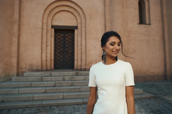 Smiling indian lady in white dress against ancient building