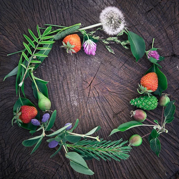 Flower and fruit wreath on wooden background