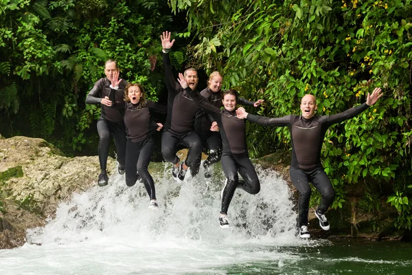 Group Of Adult People Jumping Into Small Waterfall