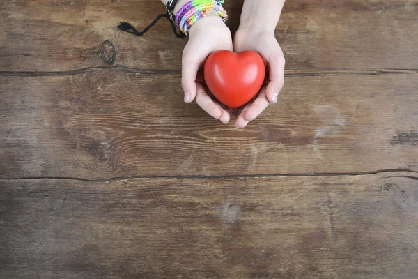 Heart in hands on wood