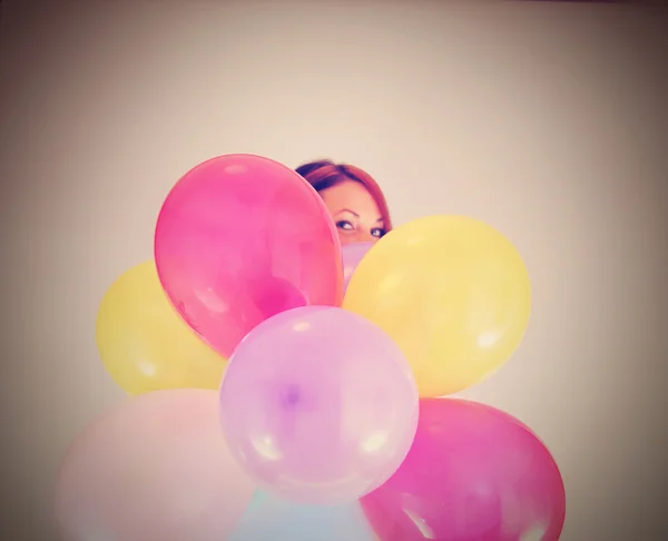 Girl hiding behind a bunch of balloons