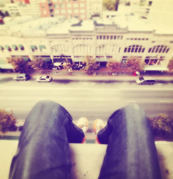 Legs hanging over tall building