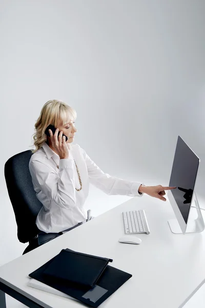 Woman at desk talking on cellphone