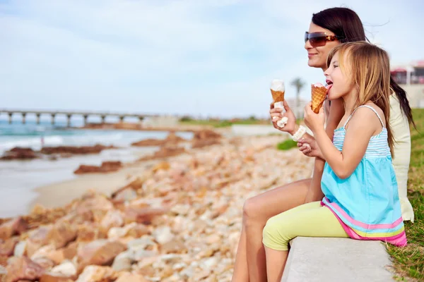 Mom and daughter enjoy ice cream at beach