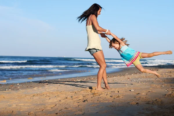 Playful mom and daughter at beach