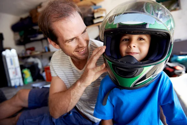 Boy playing with fathers motorbike helmet