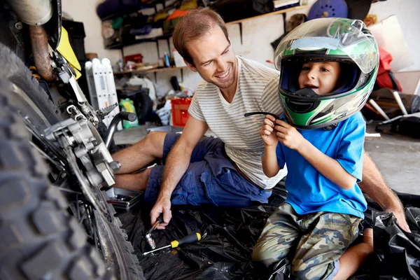 Boy playing with fathers motorbike helmet