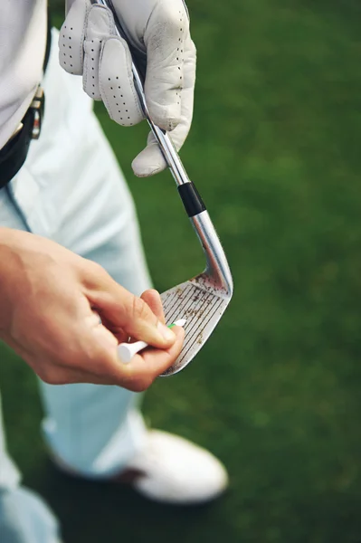 Golfer removes dirt and sand from grooves