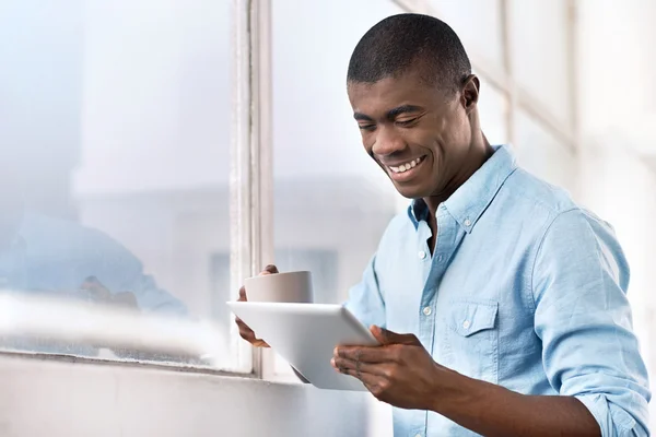 African man with coffee and tablet