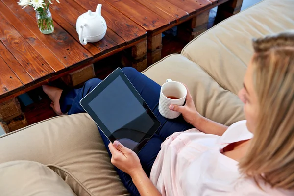 Woman on sofa reading email on tablet