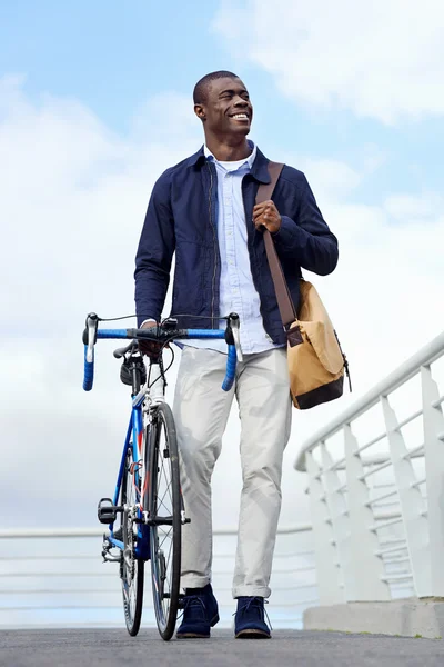 African man walking with bike in city