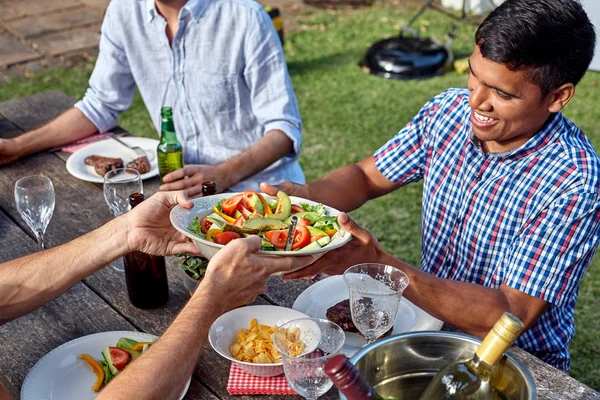 Man passing dish salad at garden party