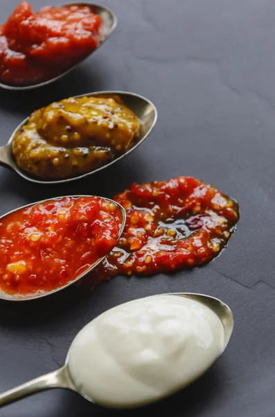 Different sauces and jams on spoons