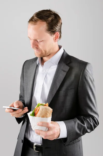 Frowning business man with lunch and mobile phone